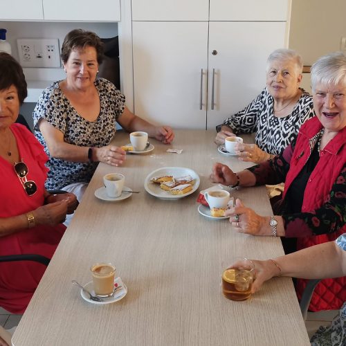 Grupo de mujeres sentada alrededor de una mesa tomando café