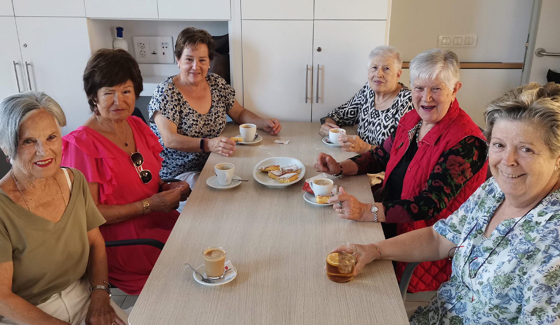 Grupo de mujeres sentada alrededor de una mesa tomando café