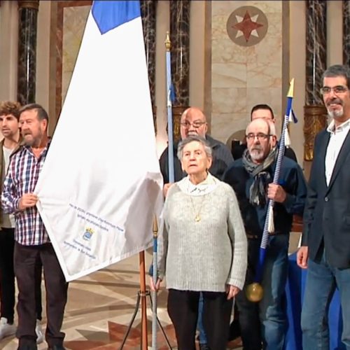 Varias personas reunidas en el ayuntamiento junto a la bandera de San Sebastián