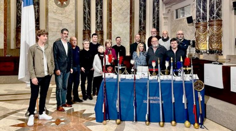 Varias personas reunidas en el ayuntamiento junto a la bandera de San Sebastián