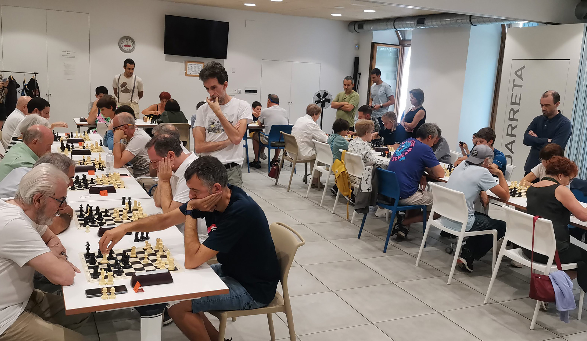 Varias mesas con gente jugando al ajedrez