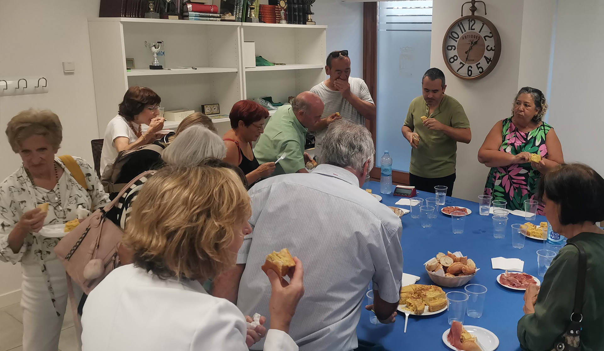 Grupo de personas comiendo de pie alrededor de una emsa