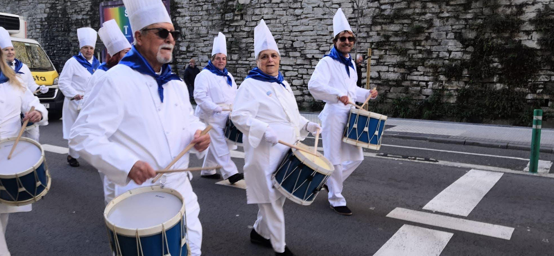grupo de personas vestidos de tamborreros tocando el tambor por la calle