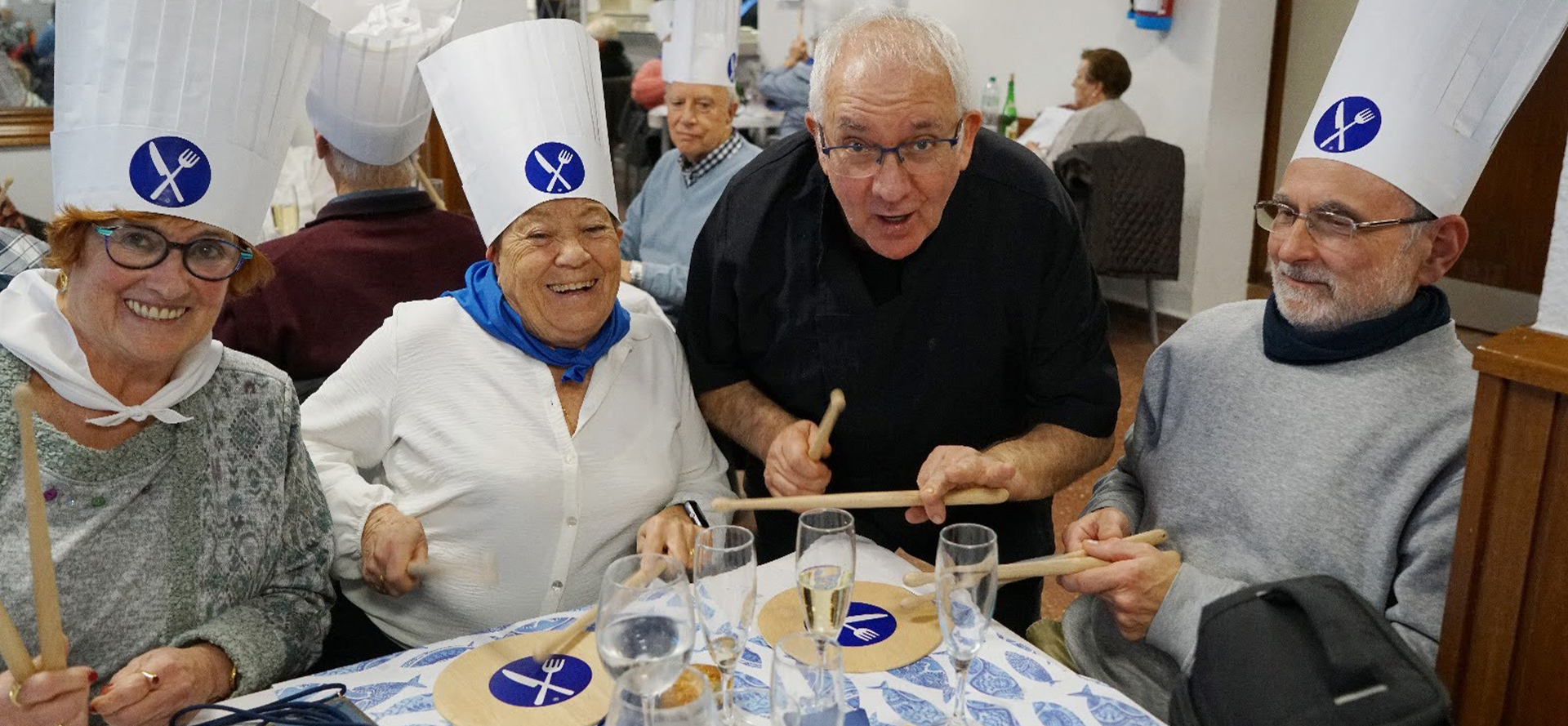 Un grupo de personas sentado a la mesa tocando con palillos en tablas