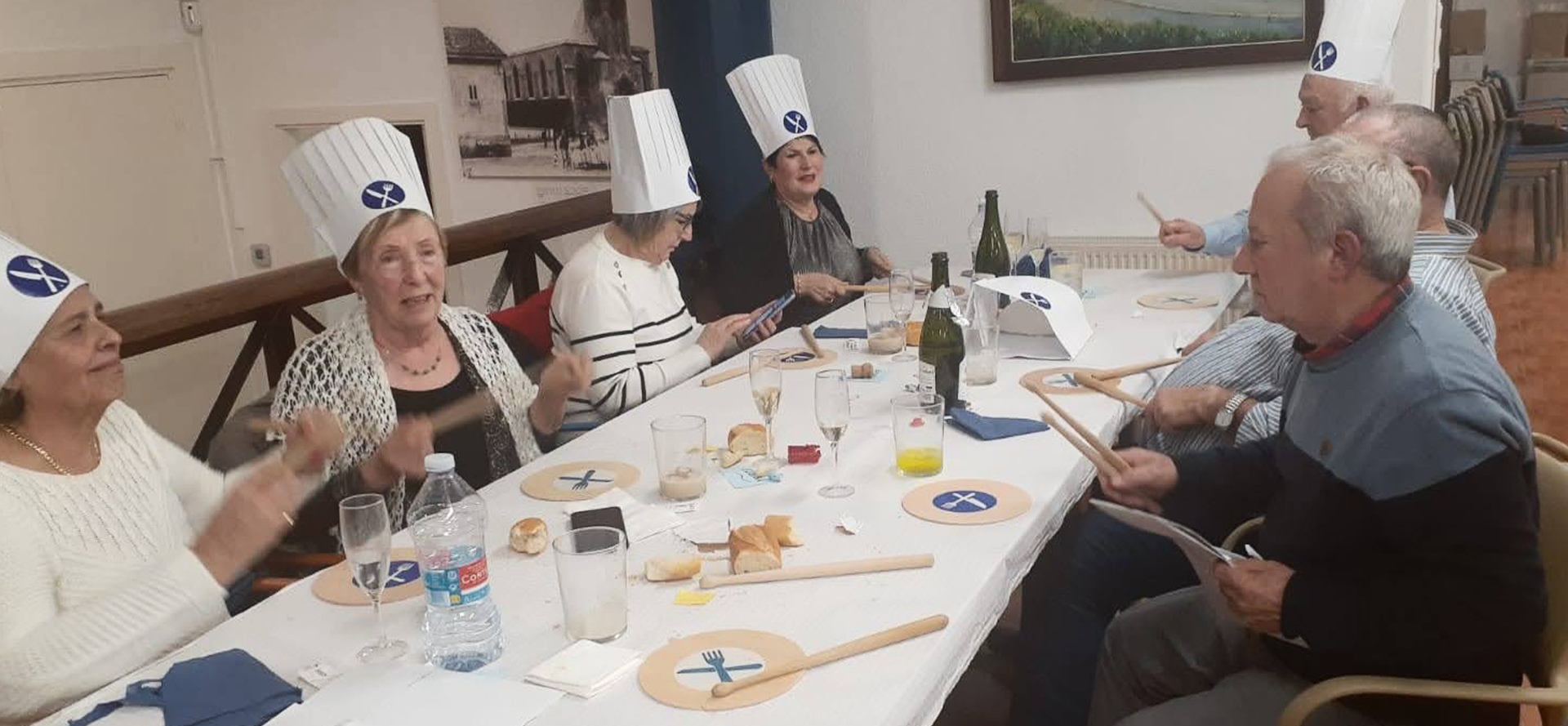 Un grupo de personas sentado a la mesa tocando con palillos en tablas