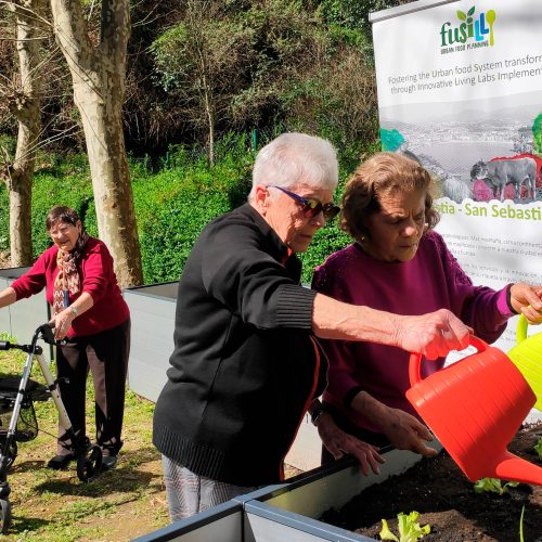 Dos personas regando una huerta con regaderas