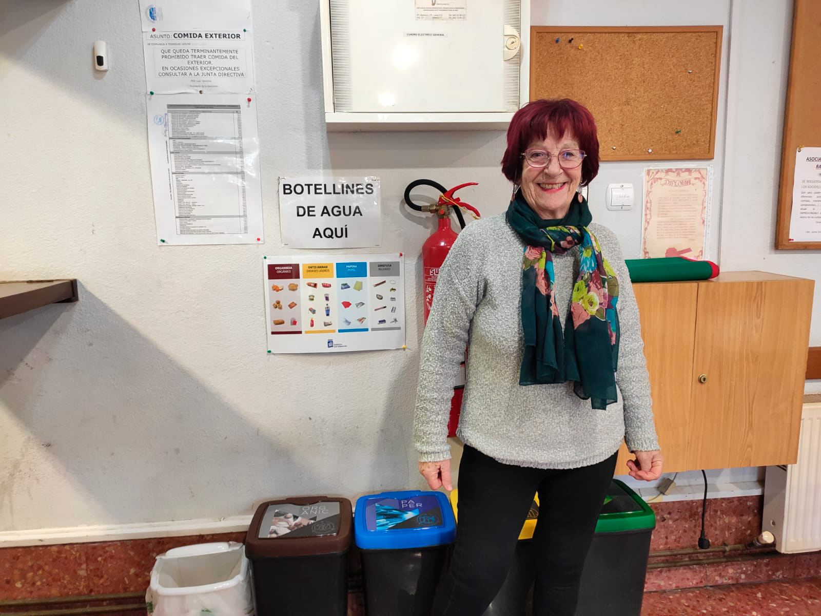 Persona posando junto a unos cubos de reciclaje a un lado