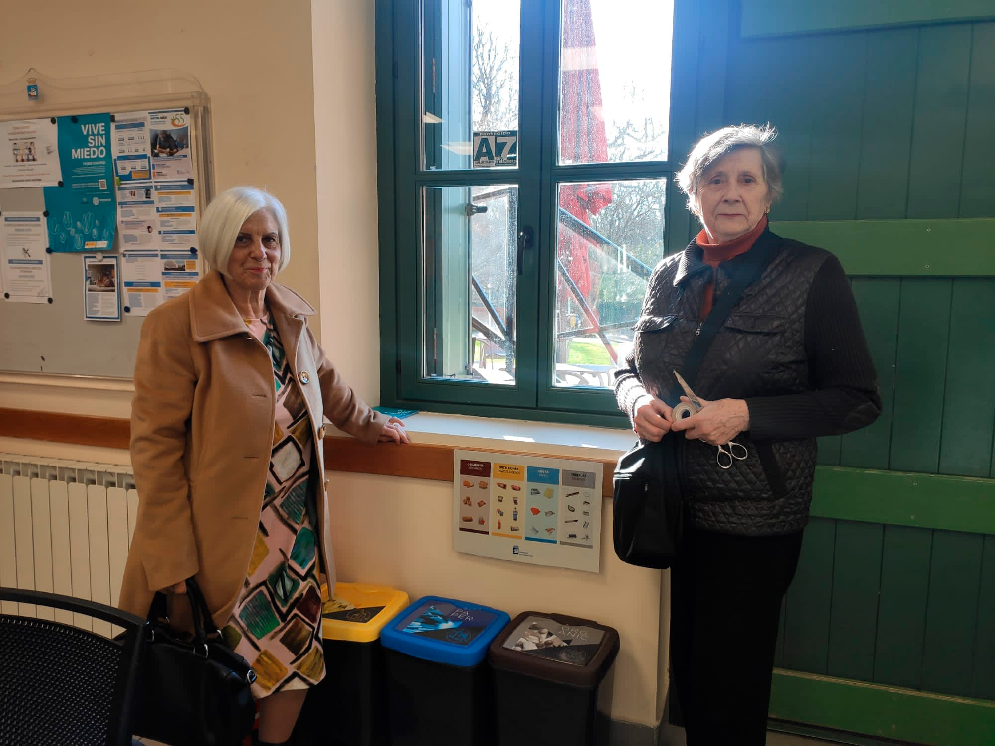 Personas posando junto a unos cubos de reciclaje a un lado