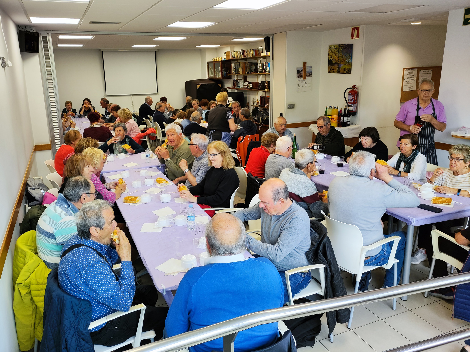Grupo de personas comiendo en varias mesas en un interior