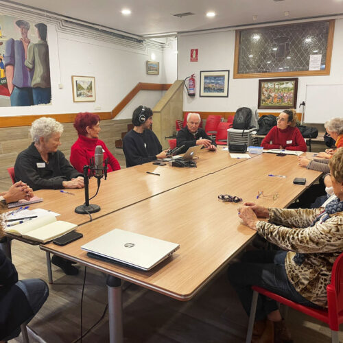 grupo de personas reunidas alrededor de una mesa, mientras un chico graba con micrófono