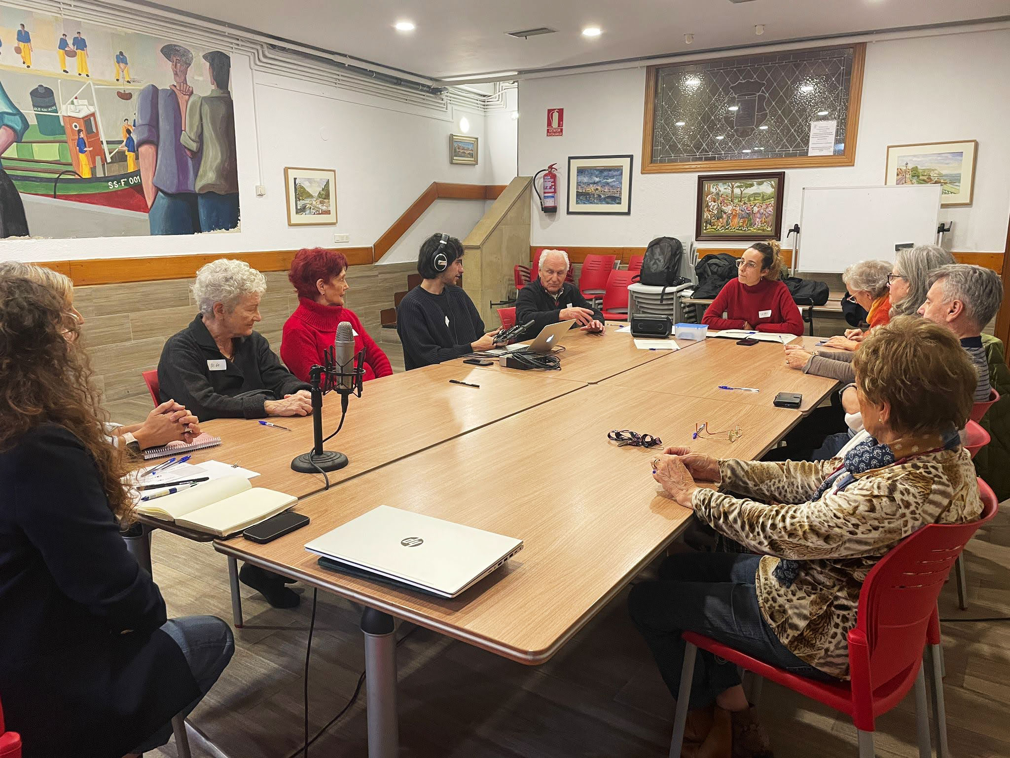grupo de personas reunidas alrededor de una mesa, mientras un chico graba con micrófono