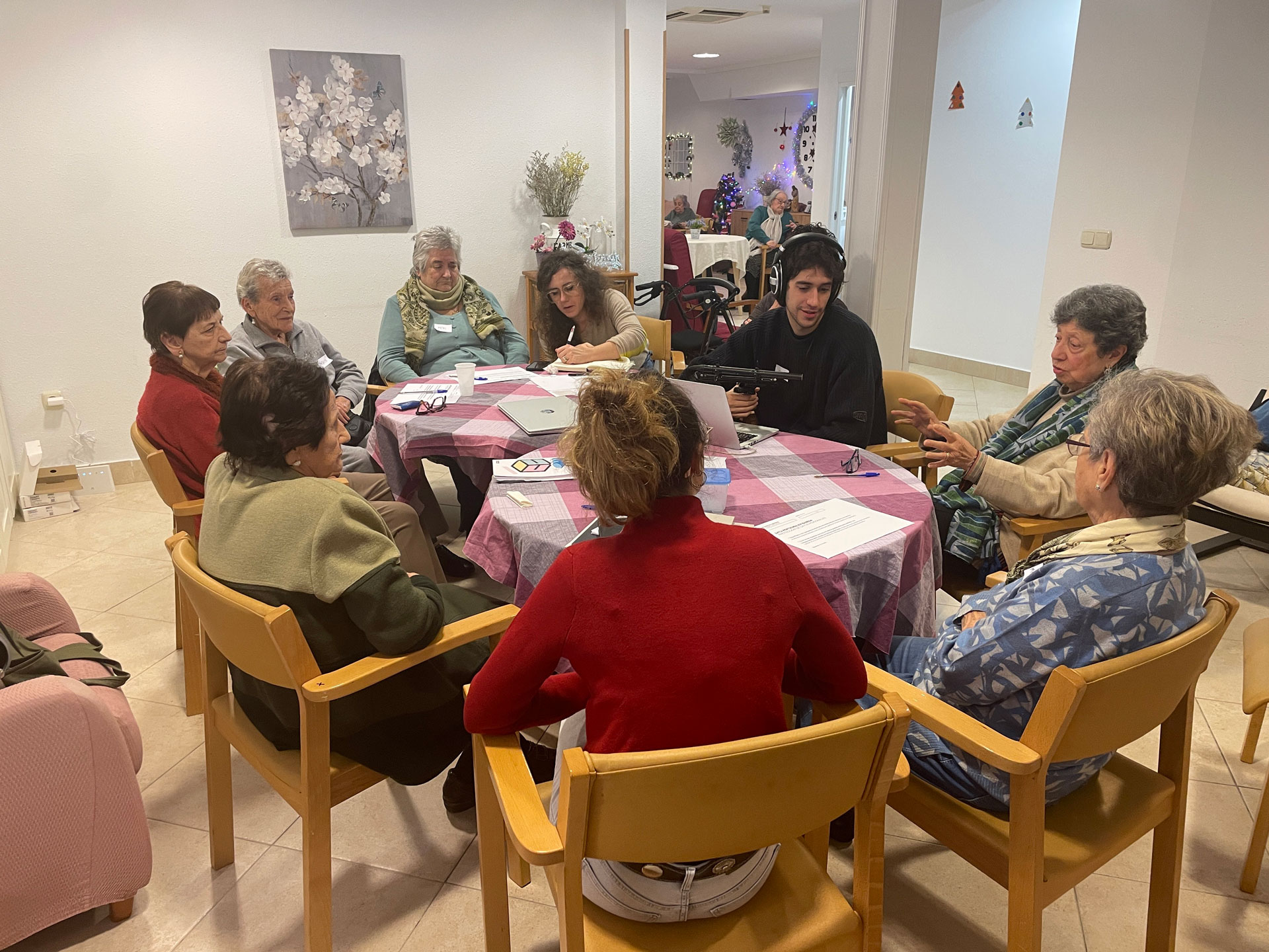grupo de personas reunidas alrededor de una mesa, mientras un chico graba con micrófono