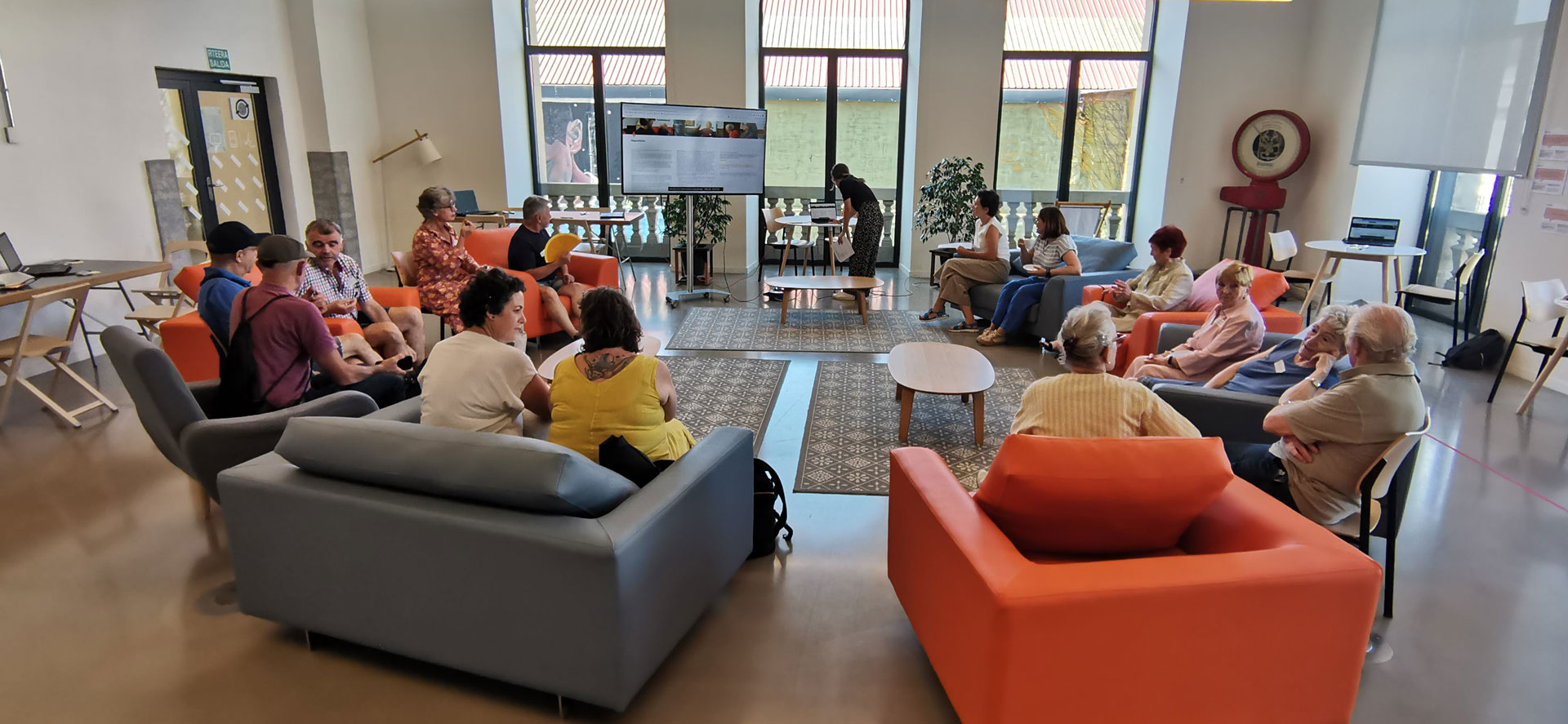 Grupo de personas reunidas en una sala frente a un monitor