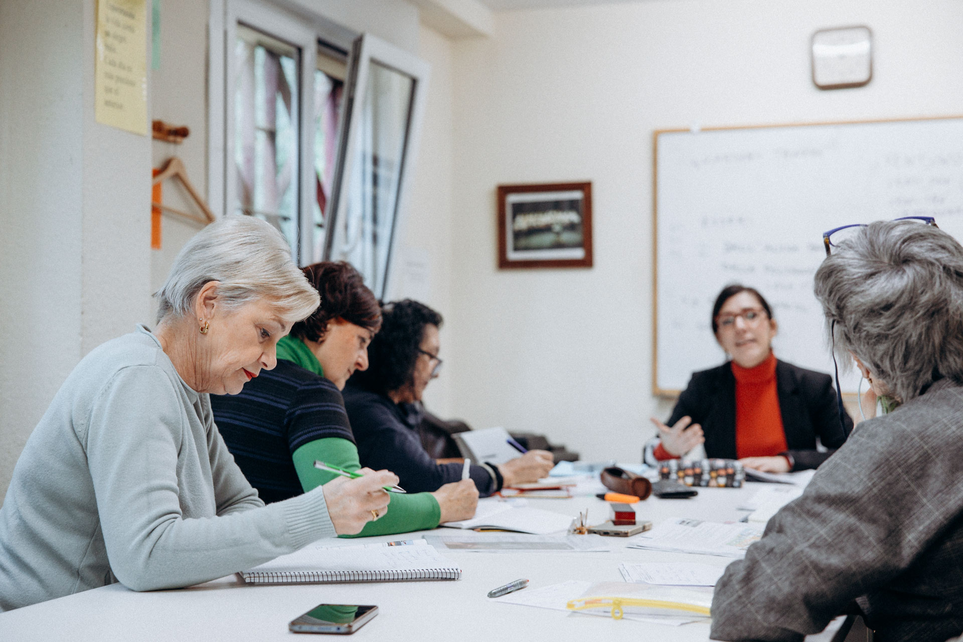 Grupo de personas alrededor de una mesa, tomando apuntes