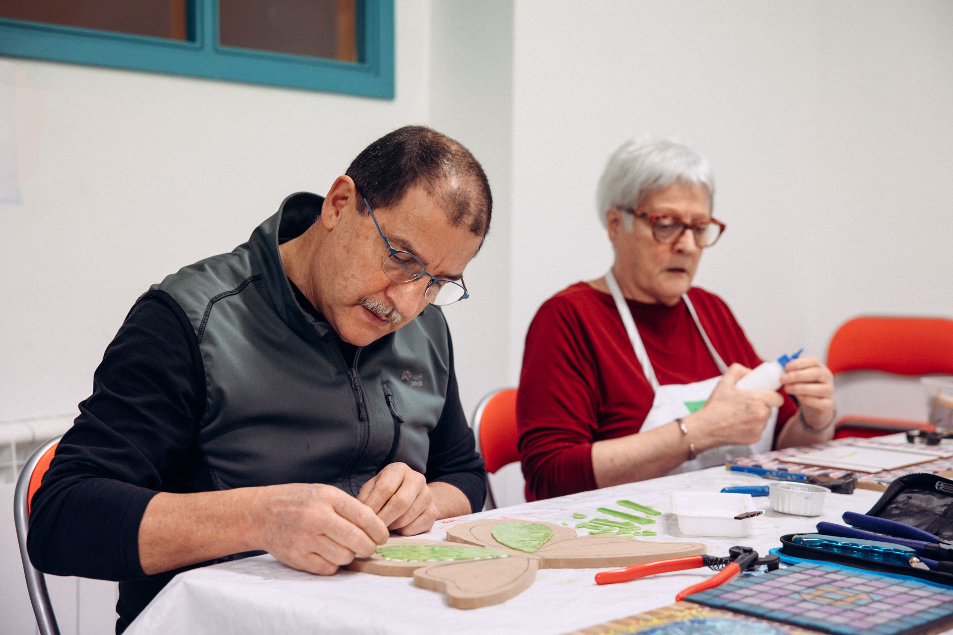 Dos personas colocando mosaicos, trabajando sobre una mesa