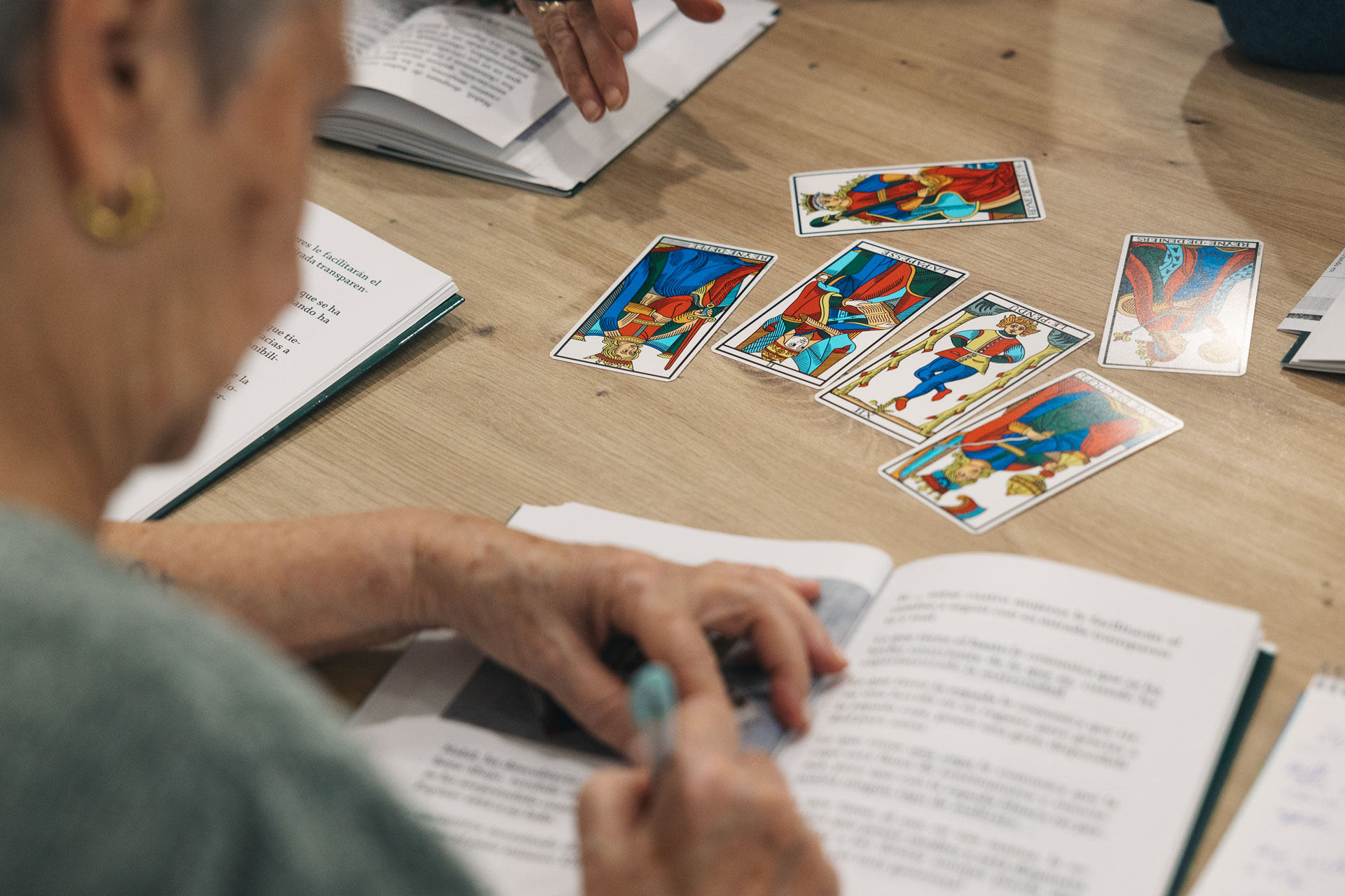 Una persona tomando notas, tiene unas cartas del Tarot a sobre la mesa