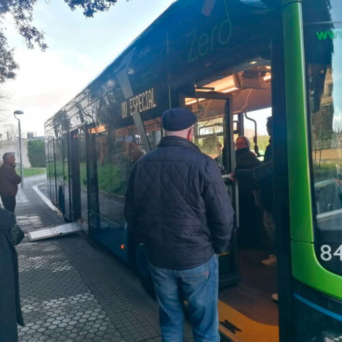Un autobús parado con las puertas abiertas y gente dentro. Y gente esperando fuera.