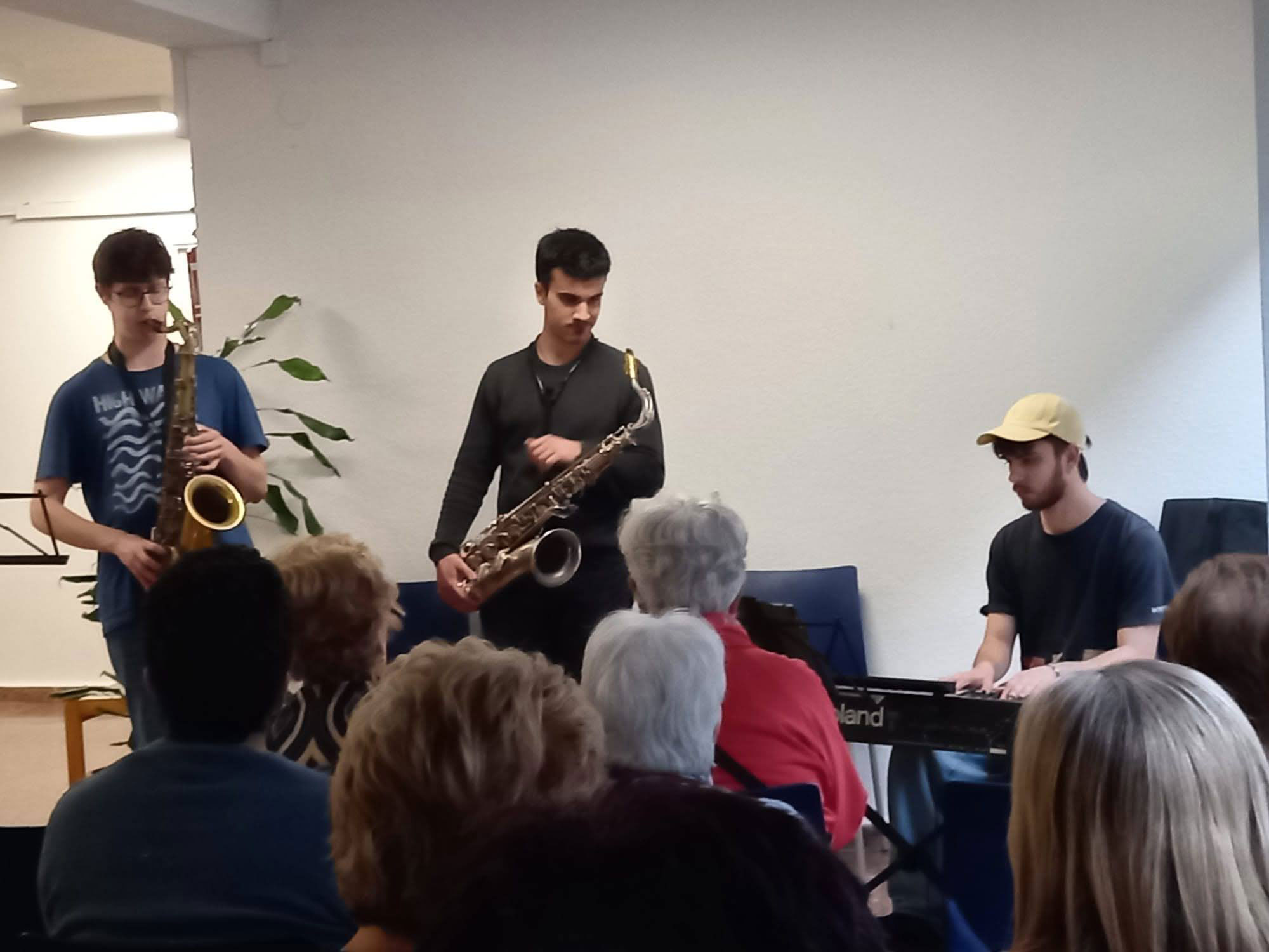 Varias personas jóvenes tocando instrumentos frente a un grupo de personas