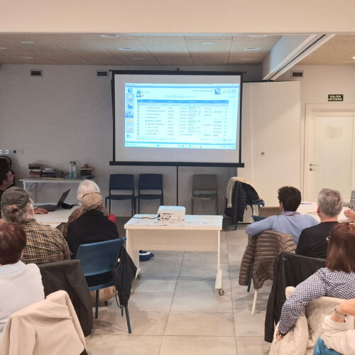 Sala llena de gente frente a una pantalla con explicaciones