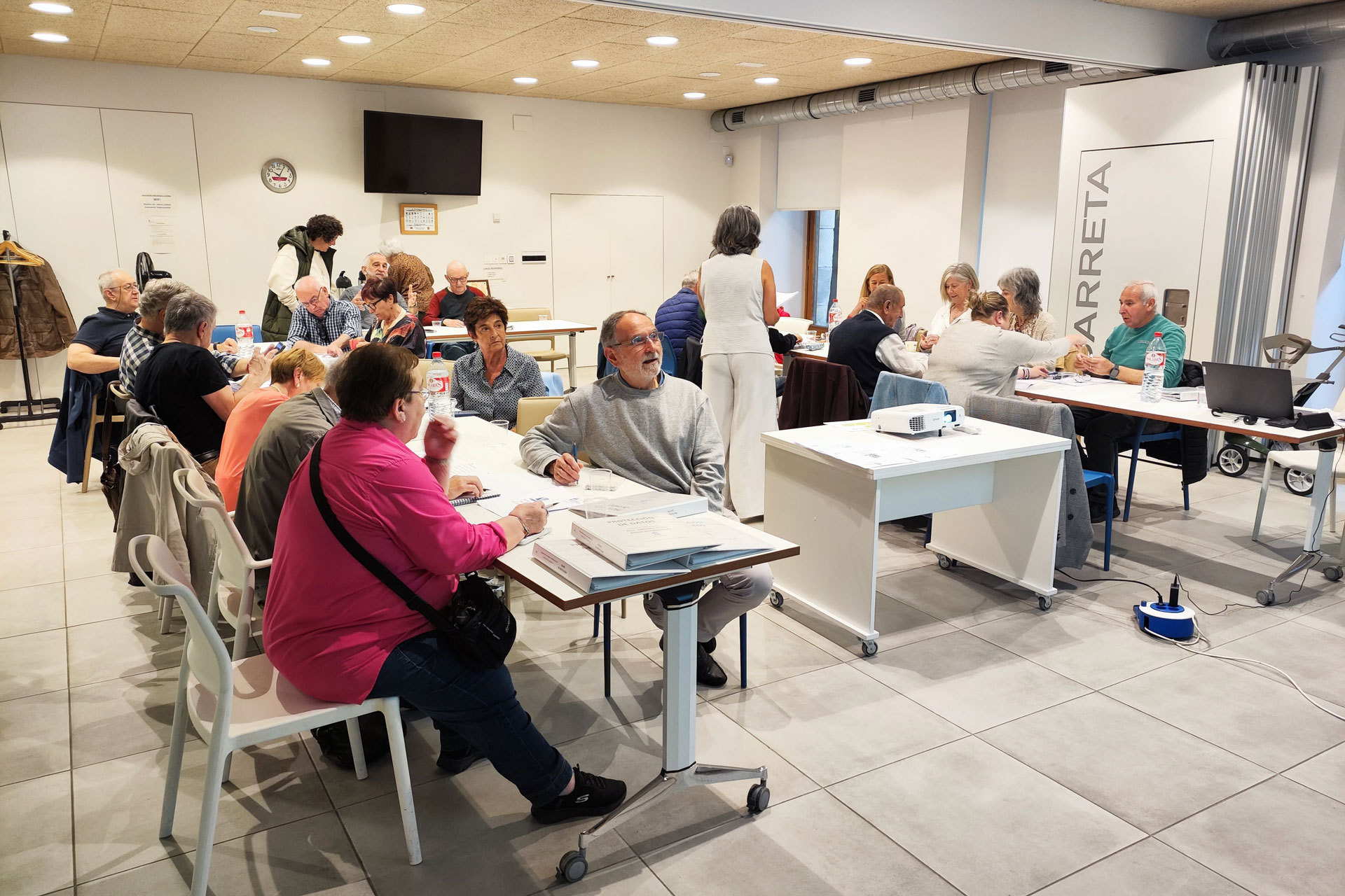 Sala llena de gente sentada frente a unas mesas