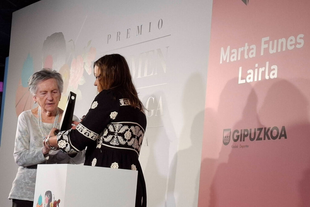 Una persona entregando un premio a otra persona frente a un atril