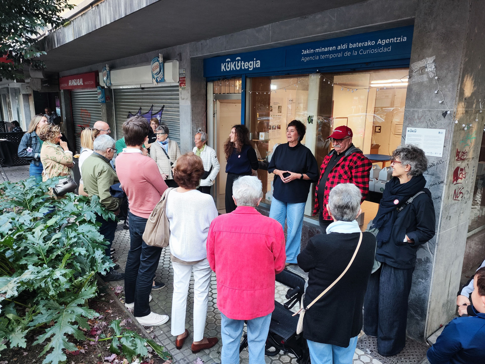 Varias personas reunidas en la calle frente a un local