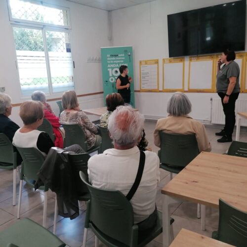 Varias personas sentadas en una sala frente a dos personas que dirigen una charla