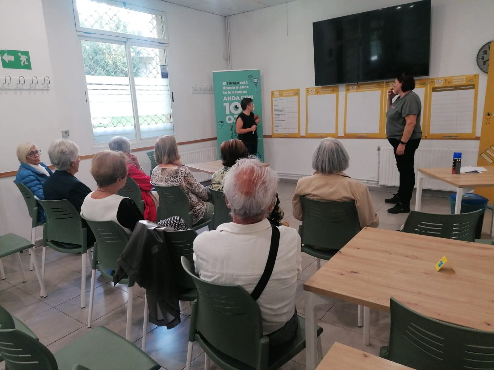 Varias personas sentadas en una sala frente a dos personas que dirigen una charla
