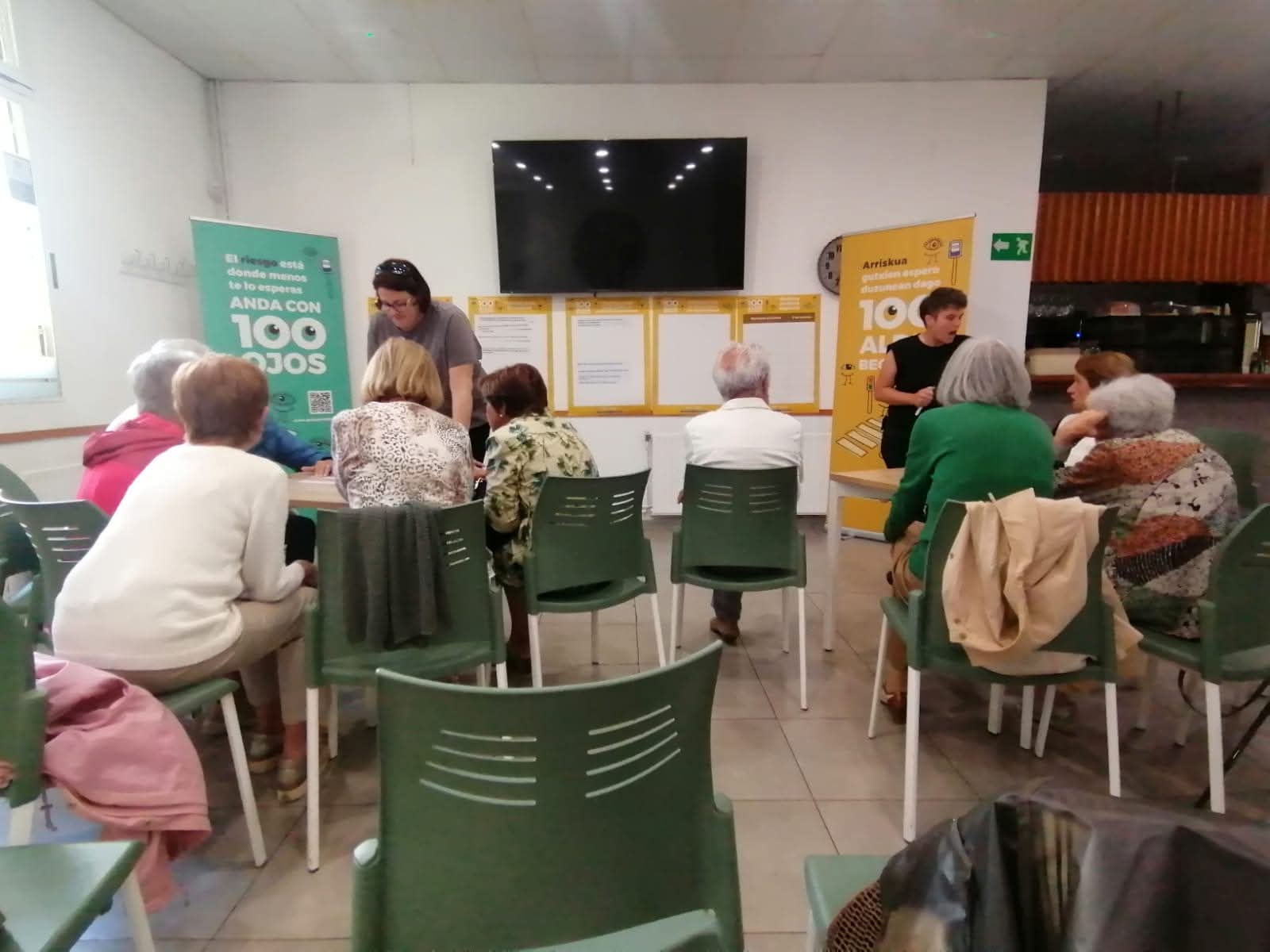 Varias personas sentadas en una sala frente a dos personas que dirigen una charla