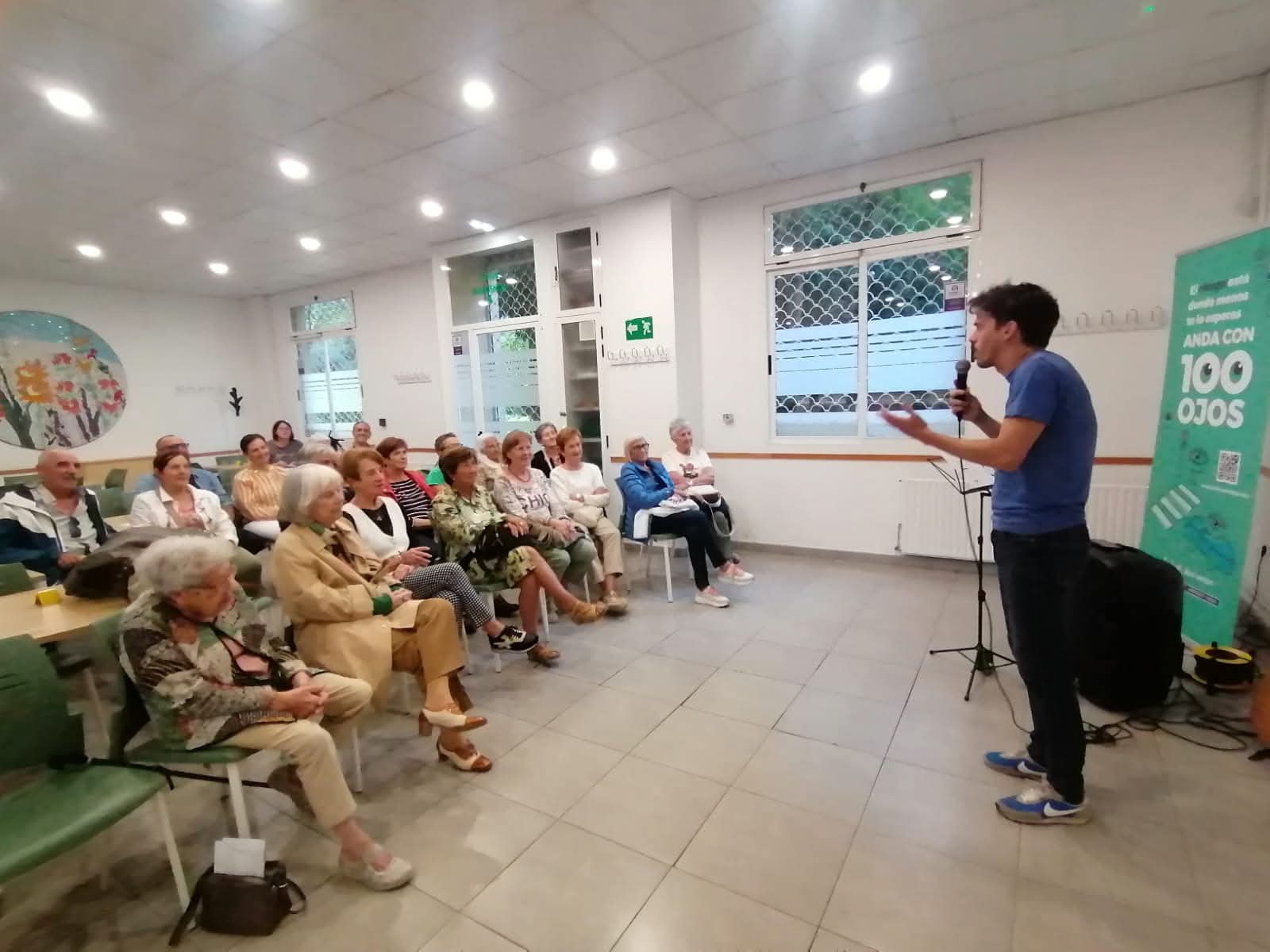 Varias personas sentadas en una sala frente a una persona con micrófono