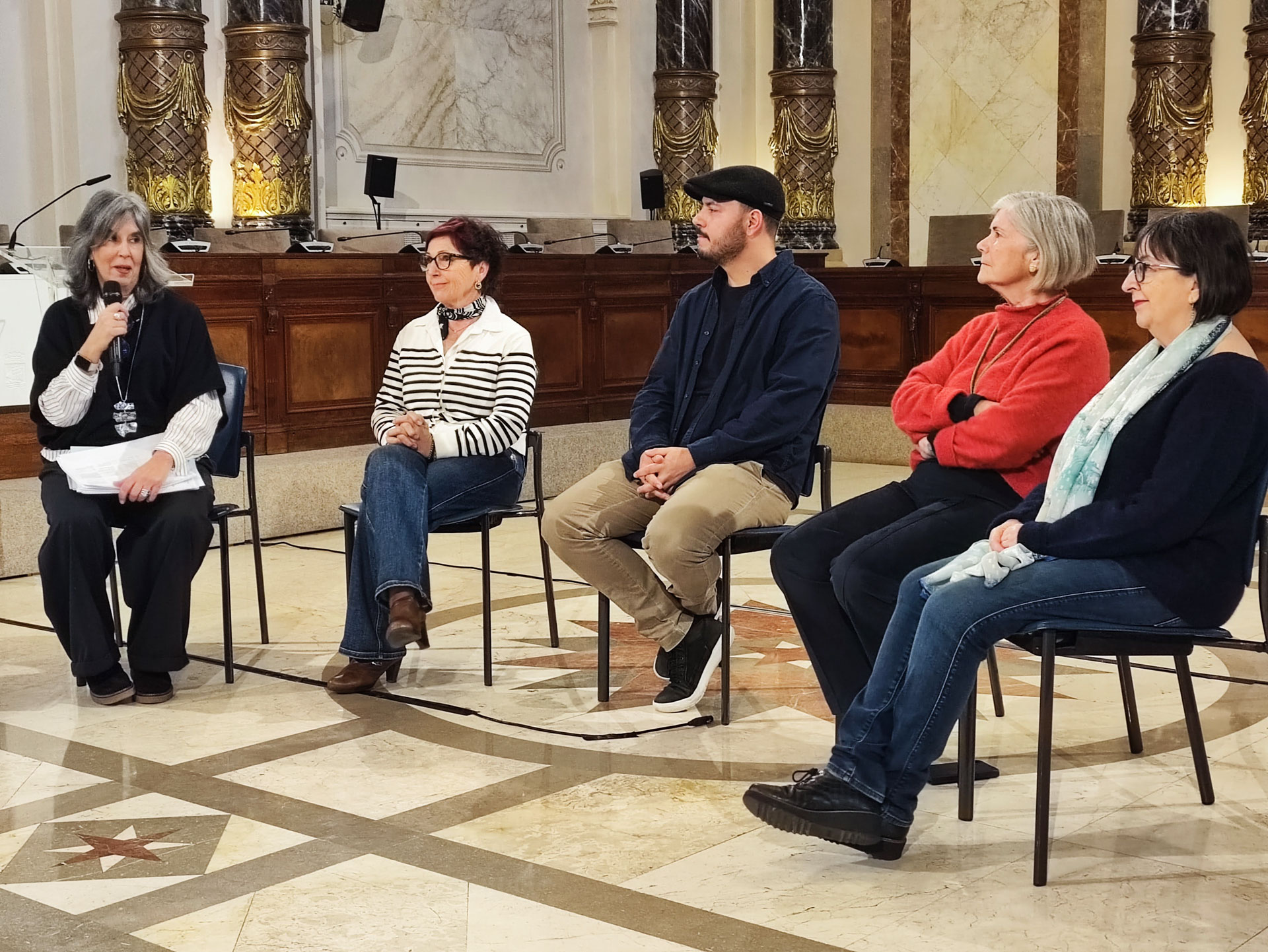 Grupo de personas reunido sentado en sillas y con micrófono