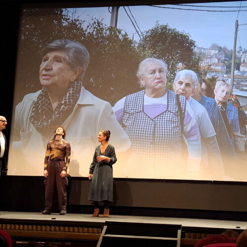 Cine con pantalla garnde e imagen, delante tres personas